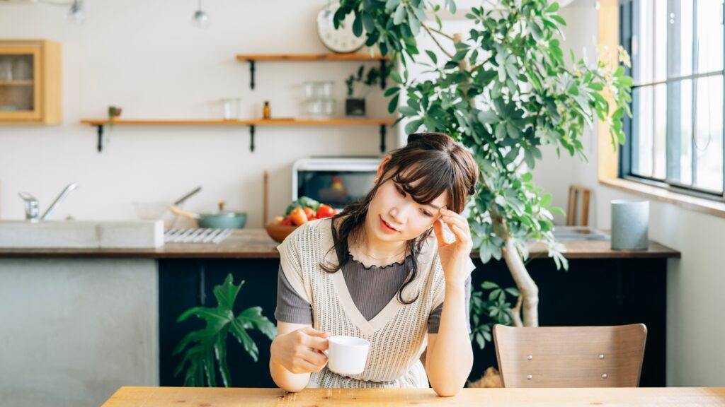 コーヒーを飲みながら悩む女性
