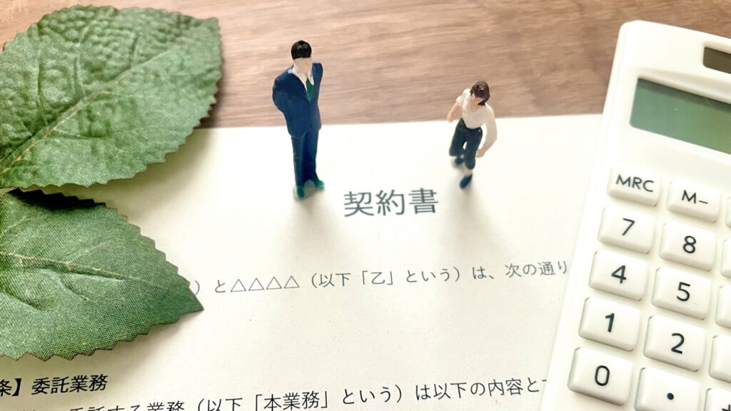 契約書うえにビジネスマンと女性の人形