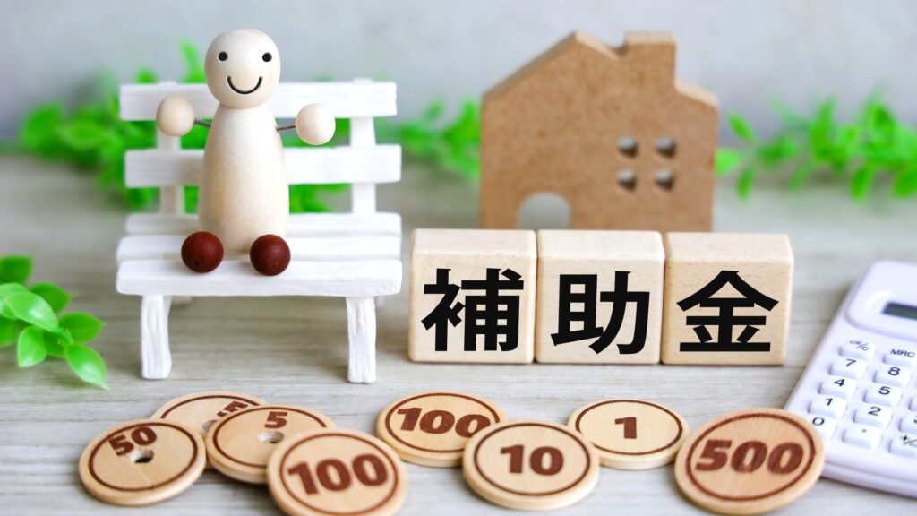 家の模型、補助金の文字、人形、お金